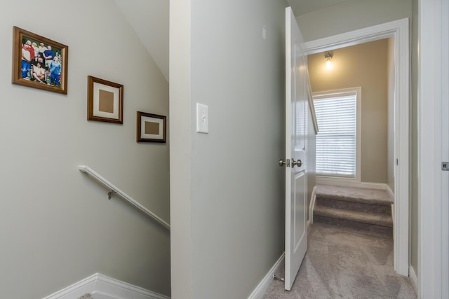 hall with lofted ceiling and light colored carpet