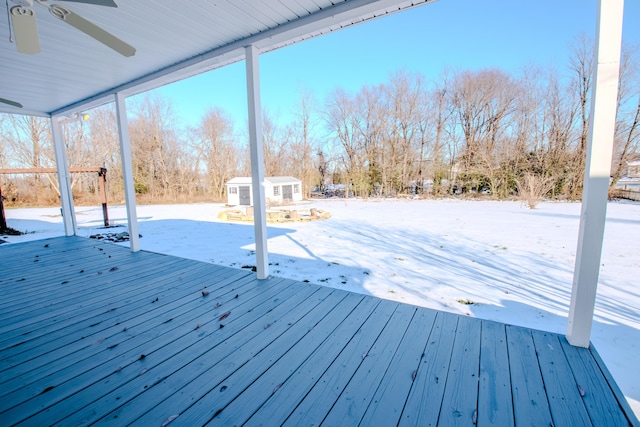 snow covered deck featuring ceiling fan and a shed