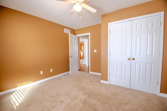 unfurnished bedroom featuring ceiling fan, light colored carpet, and a closet