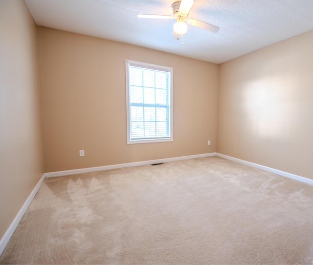 spare room with ceiling fan, a textured ceiling, and carpet flooring