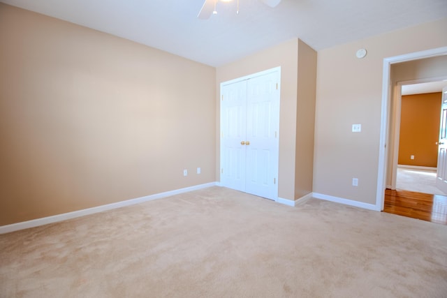 unfurnished bedroom featuring ceiling fan, light colored carpet, and a closet