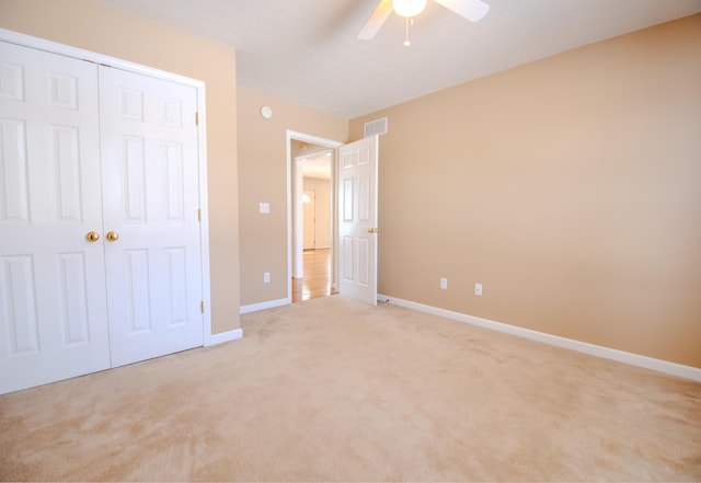 unfurnished bedroom featuring light carpet, ceiling fan, and a closet