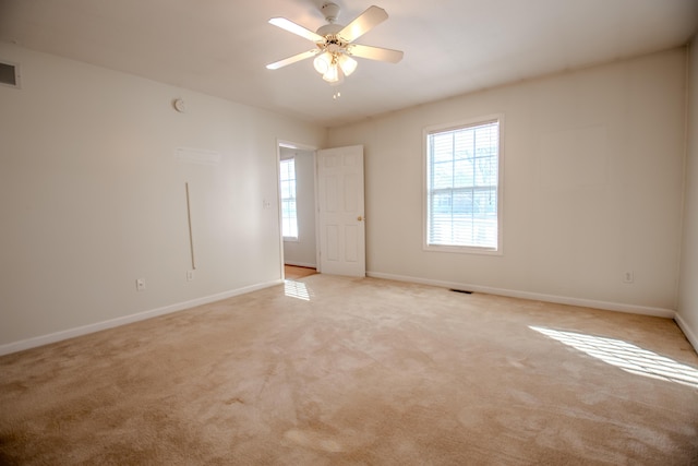 unfurnished room with ceiling fan, light colored carpet, and a wealth of natural light