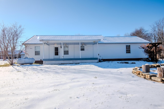 snow covered back of property featuring a porch