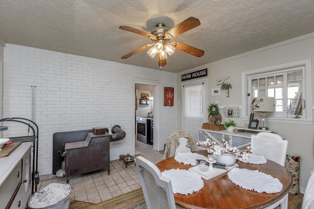 dining space with ceiling fan, light hardwood / wood-style flooring, a textured ceiling, and brick wall