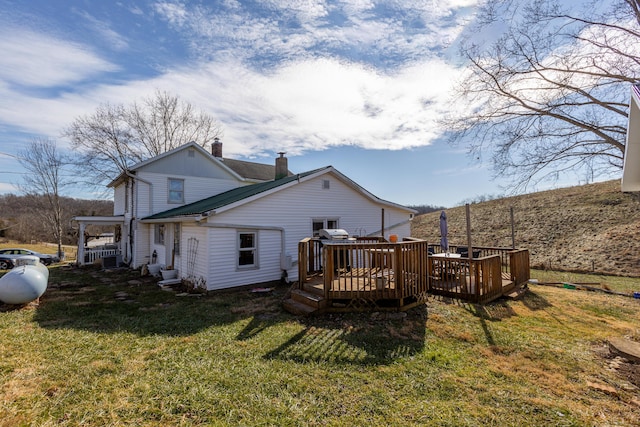 back of property with a wooden deck and a lawn