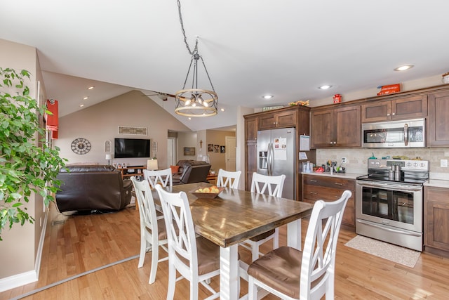 dining area with light hardwood / wood-style flooring, a chandelier, and vaulted ceiling