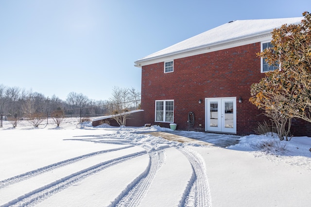 snow covered back of property with french doors