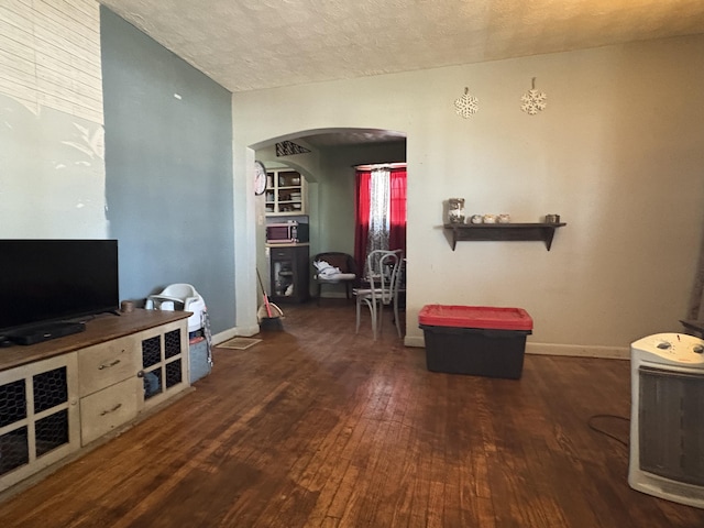 living room with dark hardwood / wood-style flooring and a textured ceiling