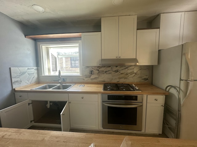 kitchen featuring sink, stainless steel appliances, butcher block countertops, backsplash, and white cabinets