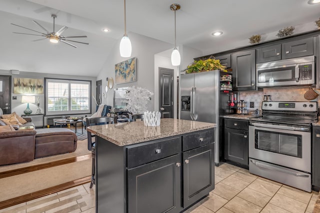 kitchen with a center island, vaulted ceiling, decorative backsplash, light stone counters, and stainless steel appliances