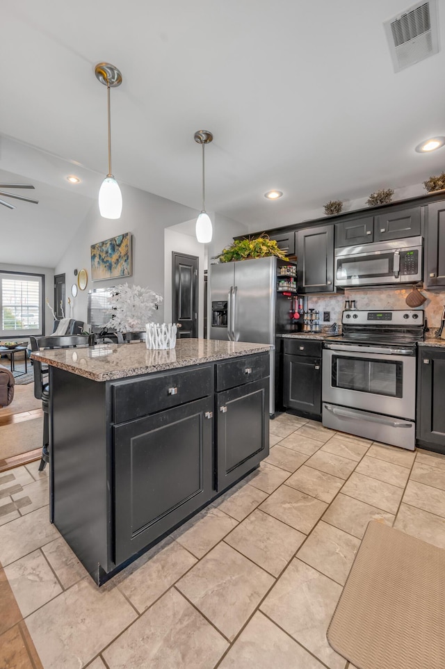 kitchen featuring light stone countertops, stainless steel appliances, vaulted ceiling, decorative light fixtures, and decorative backsplash