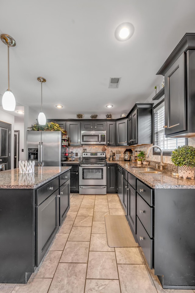 kitchen featuring hanging light fixtures, light stone counters, sink, and appliances with stainless steel finishes