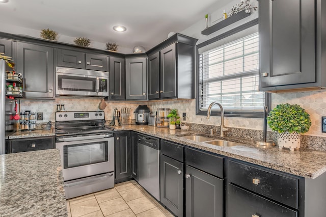 kitchen featuring stone countertops, light tile patterned floors, sink, and appliances with stainless steel finishes