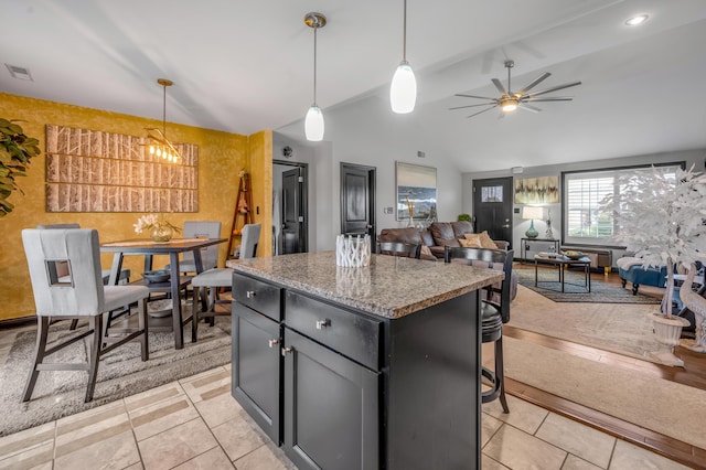 kitchen featuring ceiling fan with notable chandelier, a kitchen island, hanging light fixtures, and lofted ceiling