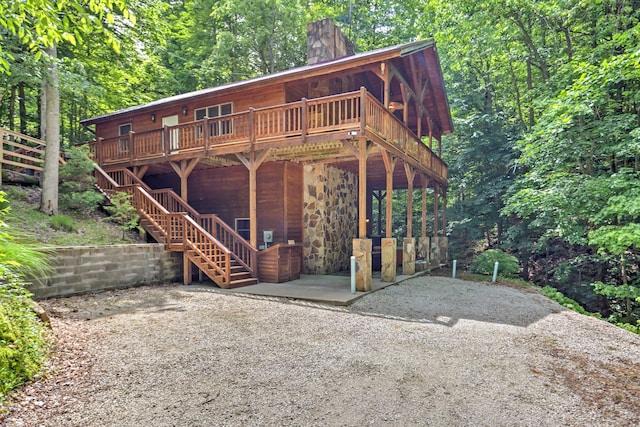 rear view of property with a wooden deck and a patio