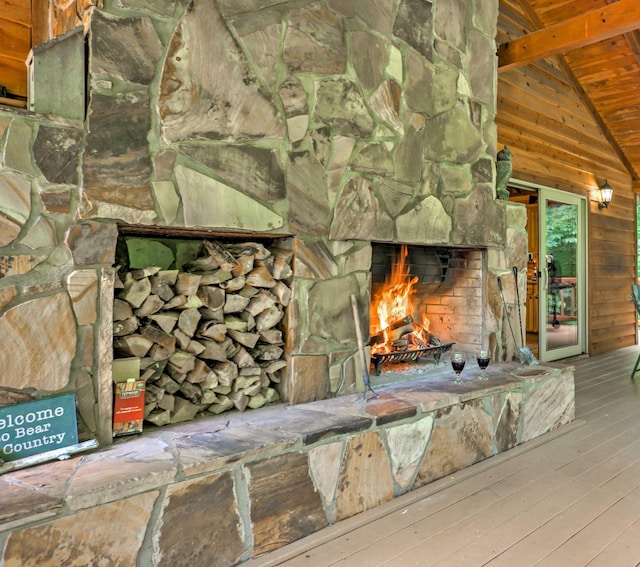 interior details with a stone fireplace, wooden walls, beamed ceiling, wood-type flooring, and wooden ceiling