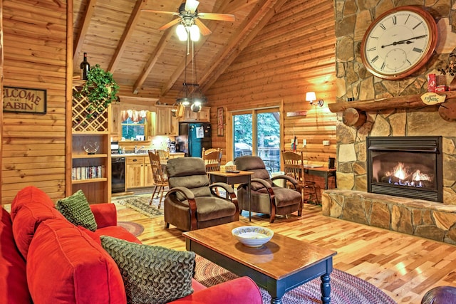 living room featuring a stone fireplace, beamed ceiling, light hardwood / wood-style floors, ceiling fan, and wooden ceiling