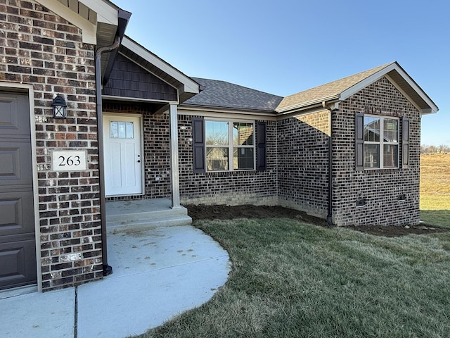 view of exterior entry with a yard and a garage