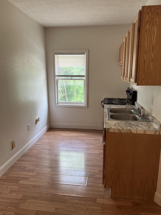 240 E Main St, Mount Vernon, KY 40456 - kitchen featuring light countertops, brown cabinets, light wood-type flooring, and a textured ceiling