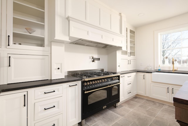 kitchen with range with two ovens, white cabinetry, and sink