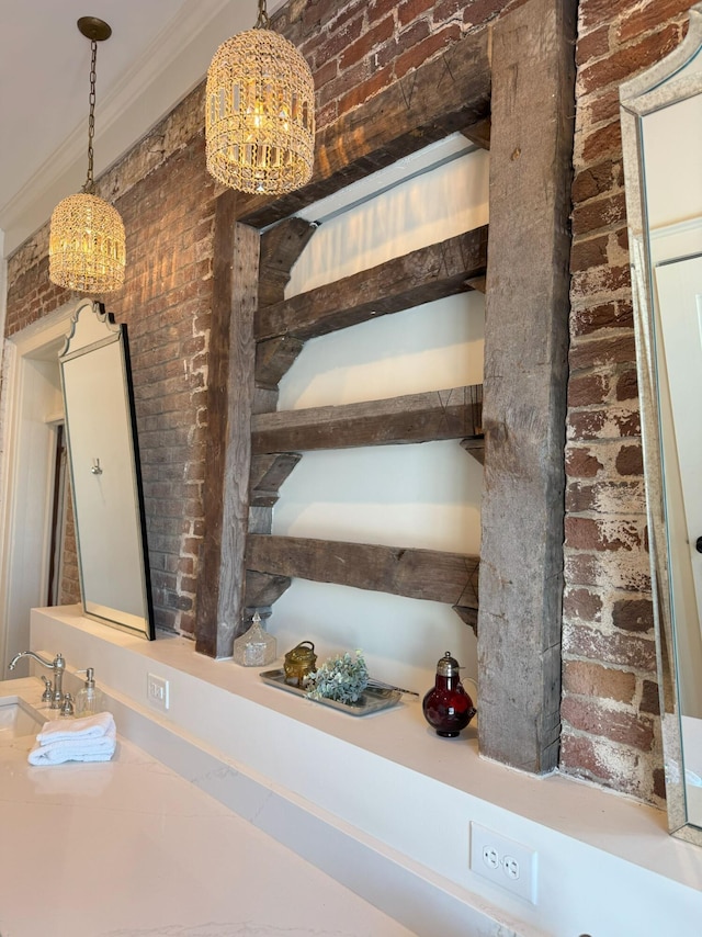 stairway featuring a chandelier, crown molding, sink, and brick wall