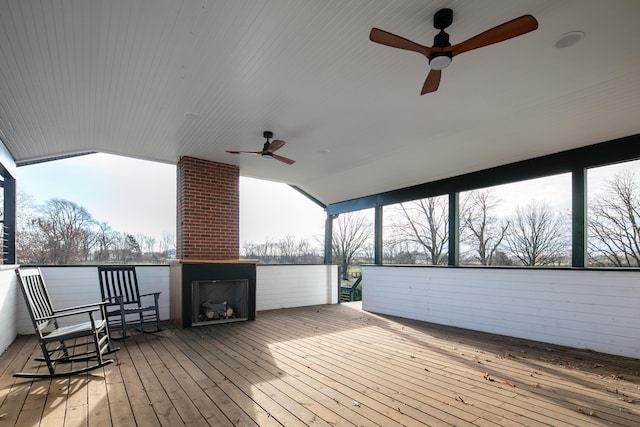 wooden deck featuring a large fireplace and ceiling fan