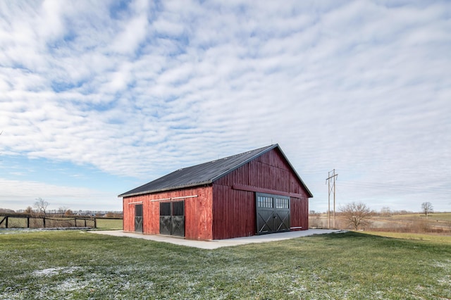 view of outbuilding with a lawn and a rural view