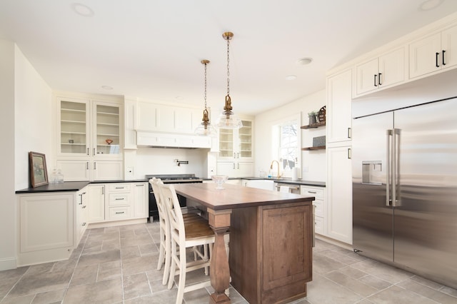 kitchen with a kitchen bar, a kitchen island, high end appliances, white cabinetry, and hanging light fixtures