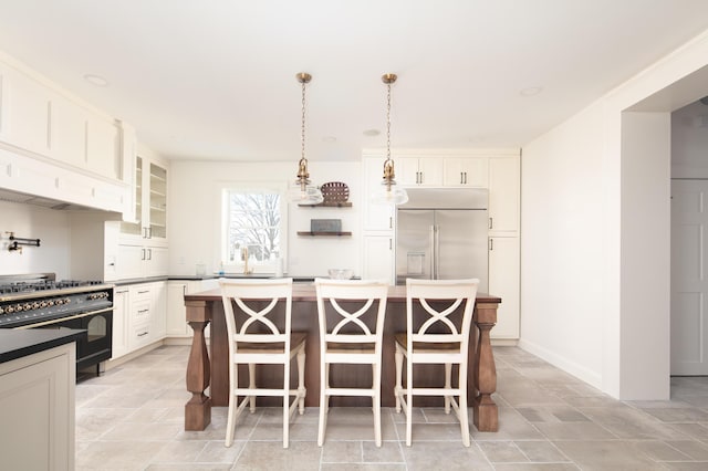 kitchen featuring a breakfast bar, a kitchen island, pendant lighting, high quality appliances, and white cabinetry