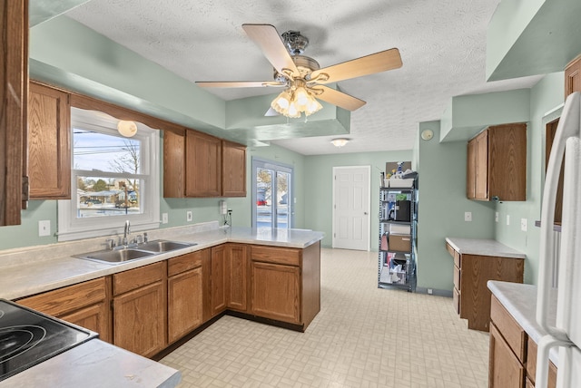 kitchen with sink, white refrigerator, a textured ceiling, and kitchen peninsula