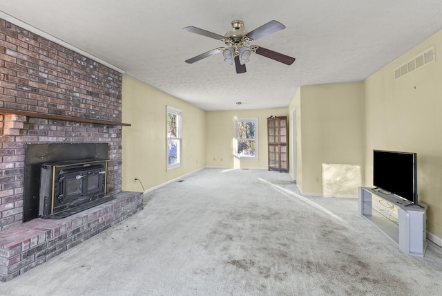 unfurnished living room with a textured ceiling, ceiling fan, a wood stove, and light carpet