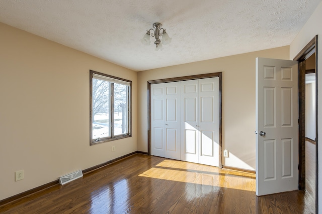 unfurnished bedroom with a textured ceiling, a closet, and dark wood-type flooring