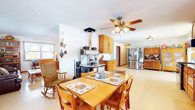 dining room featuring ceiling fan and a wood stove