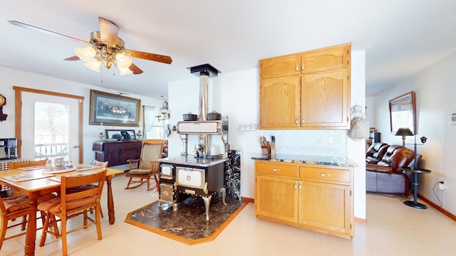 kitchen with ceiling fan, a wealth of natural light, decorative backsplash, and a wood stove