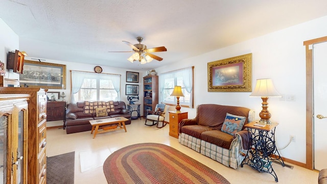 living room featuring ceiling fan and a textured ceiling