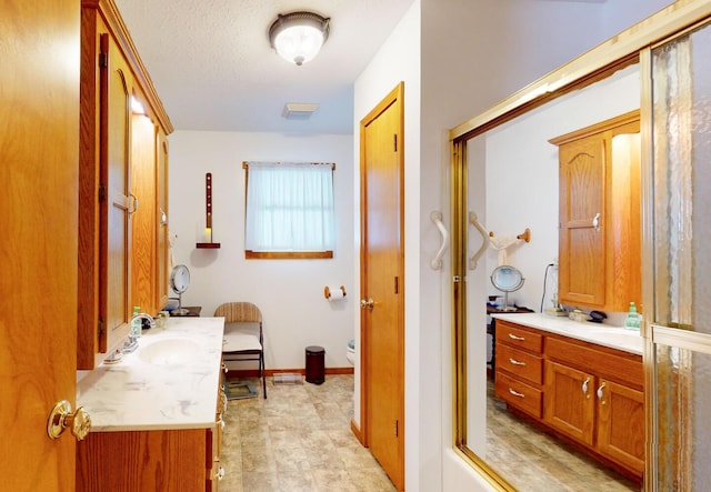 bathroom with vanity, a shower with door, and a textured ceiling