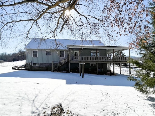 snow covered back of property with a deck