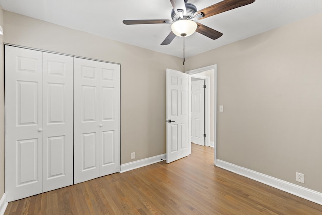 unfurnished bedroom with ceiling fan, a closet, and hardwood / wood-style floors