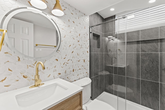 bathroom with vanity, toilet, a shower with shower door, and backsplash