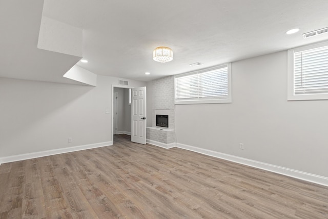 basement featuring light wood-type flooring and a fireplace