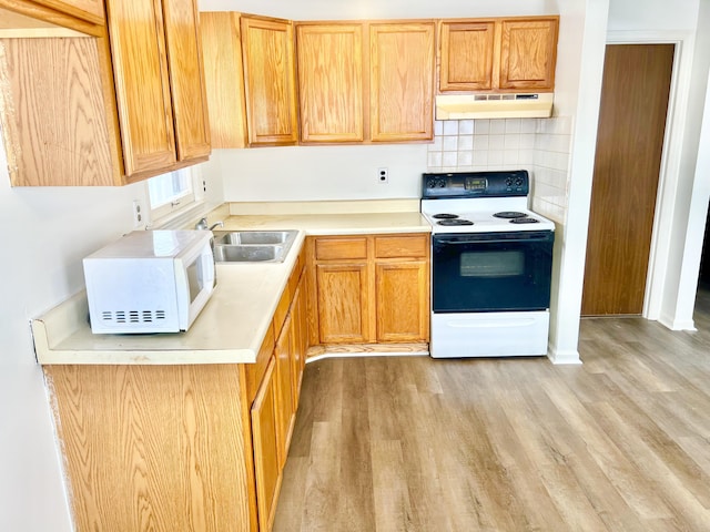 kitchen with white appliances, light hardwood / wood-style floors, tasteful backsplash, and sink