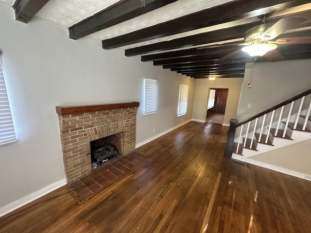 unfurnished living room with beam ceiling, dark hardwood / wood-style flooring, ceiling fan, and a fireplace