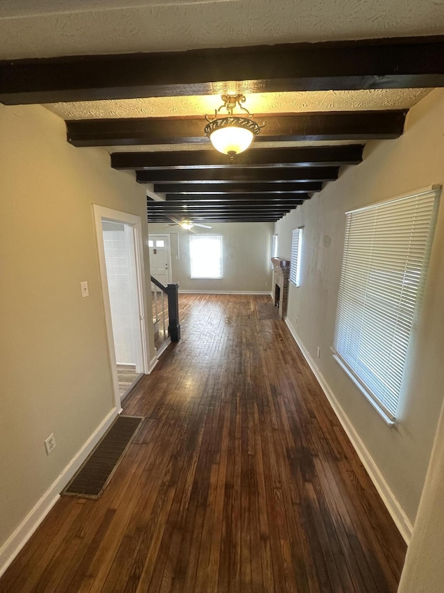 corridor with beamed ceiling and dark hardwood / wood-style flooring