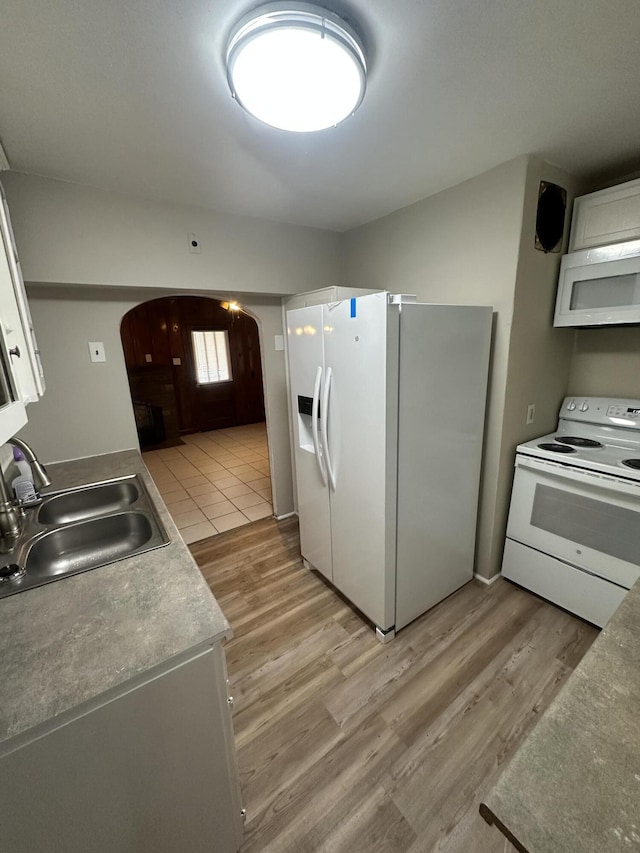 kitchen featuring white cabinetry, sink, white appliances, and light hardwood / wood-style floors