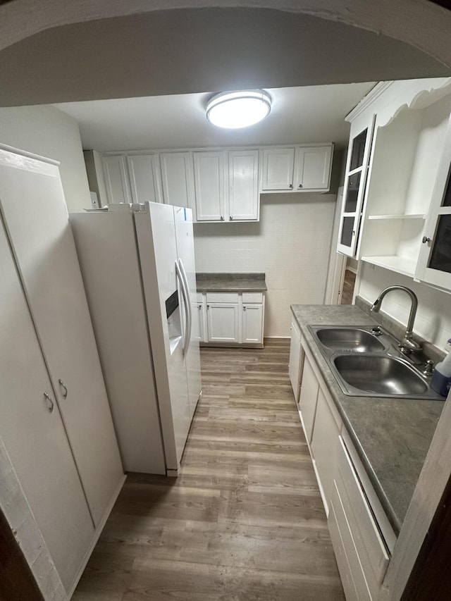 kitchen with white cabinetry, sink, white refrigerator with ice dispenser, and light hardwood / wood-style floors