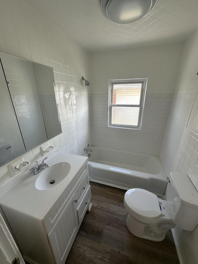 full bathroom featuring tiled shower / bath, wood-type flooring, tile walls, vanity, and toilet