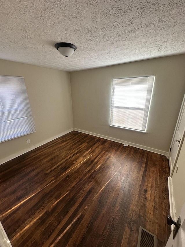 spare room featuring dark hardwood / wood-style flooring and a textured ceiling