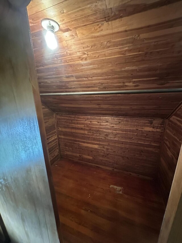 bonus room featuring lofted ceiling, dark wood-type flooring, and wood walls