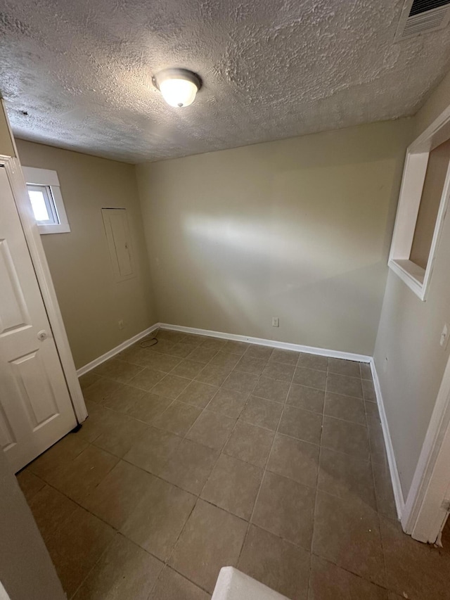 tiled spare room with a textured ceiling